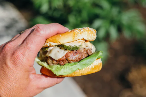 Close-up of someone holding a delicious, grass-fed burger