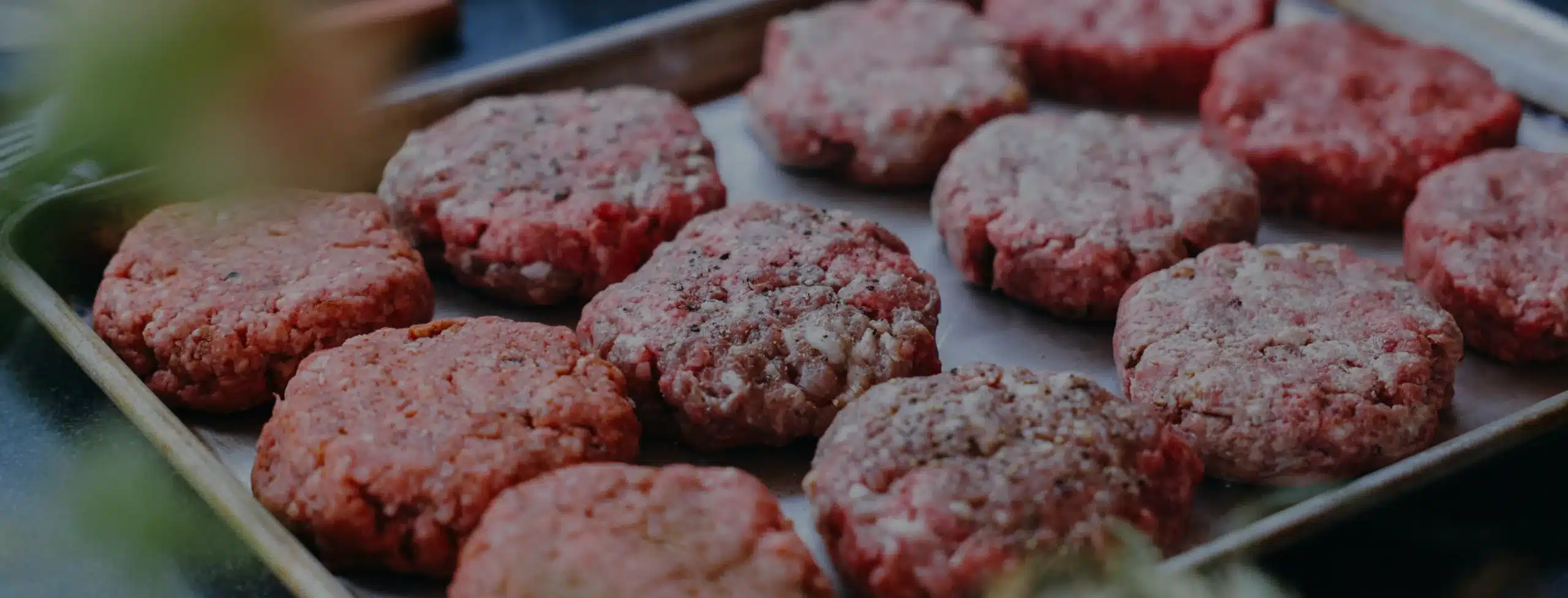 Grass fed burger patties on a tray, ready to be cooked